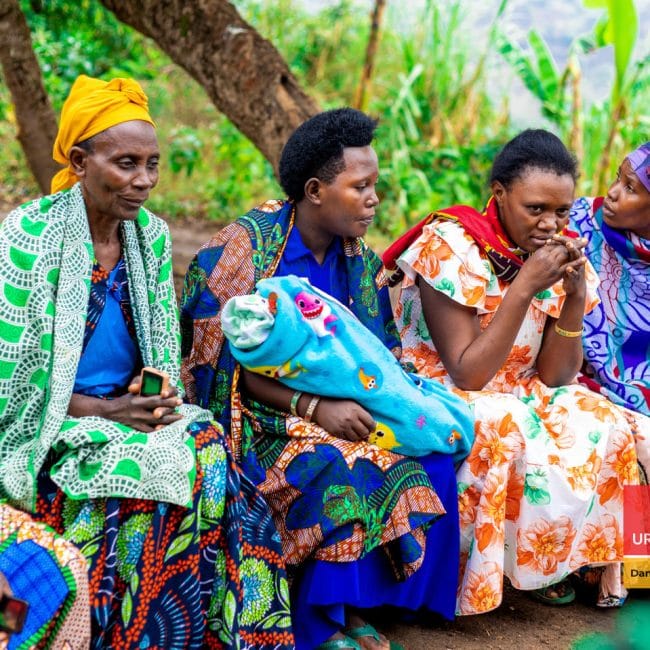 three women with colourful outfits sitting on a bench attending a training
